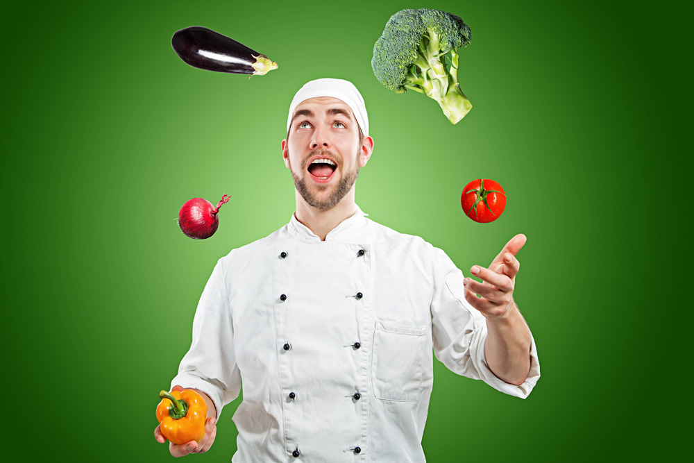Ein Koch jongliert Gemüse vor einem grünen Hintergrund.